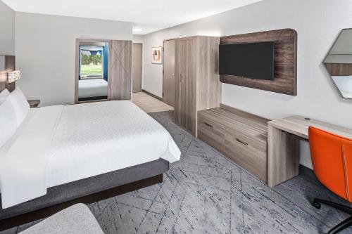 a hotel room with a bed and a flat screen tv at Holiday Inn Express Hotel & Suites Chicago-Algonquin by IHG in Algonquin