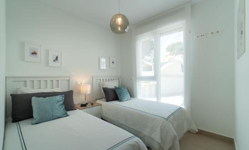2 camas en una habitación con ventana en Brisa Puerto Marina Apartments, en Benalmádena