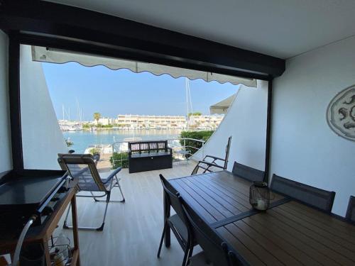une terrasse avec une table et des chaises et une vue sur l'eau dans l'établissement Marina sur Port Camargue, au Grau-du-Roi