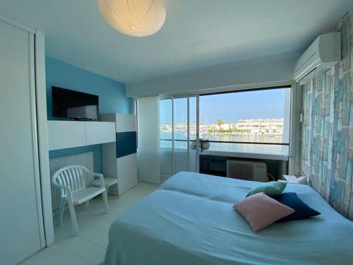 une chambre avec un lit et une grande fenêtre dans l'établissement Marina sur Port Camargue, au Grau-du-Roi