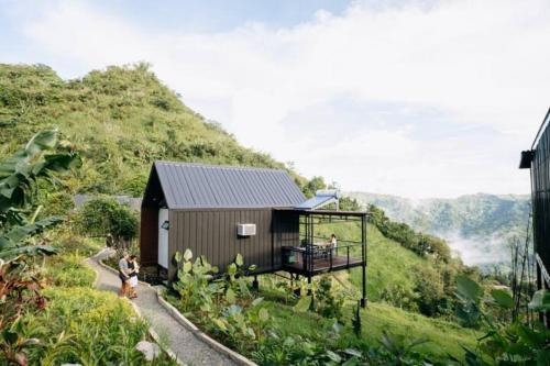 a small house on a hill with people standing on a balcony at Grey Rock Mountain Cabin w/ Jacuzzi in Balamban