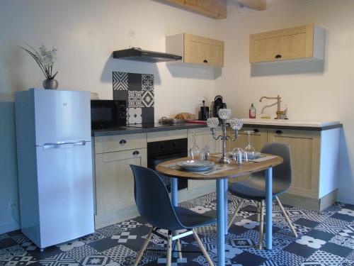uma cozinha com uma mesa com cadeiras e um frigorífico em love room La gondole du plaisir em Saint-Pierre-dʼAmilly