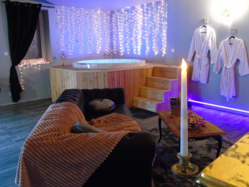 uma sala de estar com uma banheira, um sofá e uma vela em love room La gondole du plaisir em Saint-Pierre-dʼAmilly