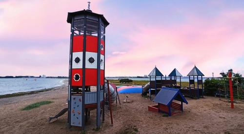 a red and white lighthouse on the beach at Mietwohnwagen in wulfener hals Fehmarn in Fehmarn