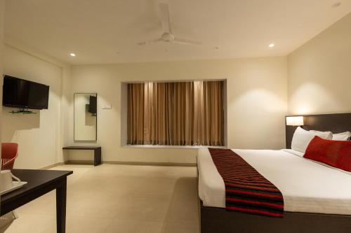 ein Hotelzimmer mit einem Bett und einem Fenster in der Unterkunft Freesia Residency by Express Inn in Nashik