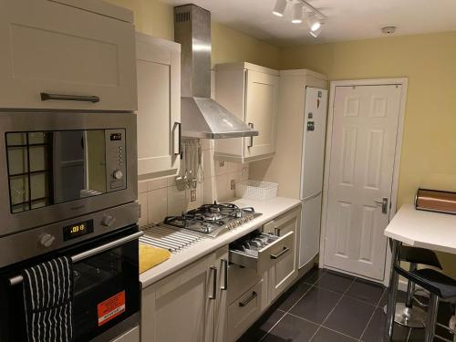 a kitchen with white cabinets and a stove top oven at Rooms at EEJ homes in London