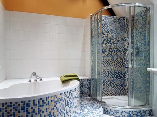 a bathroom with a tub and a shower with blue tiles at Haus Pinkafeld Top 2 in Pinkafeld