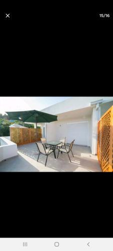 un patio con 2 mesas y una sombrilla verde en Home REX, en Ulcinj