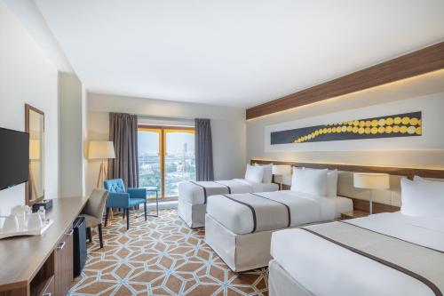 een hotelkamer met 2 bedden en een televisie bij Blue Coral Hotel in Mekka
