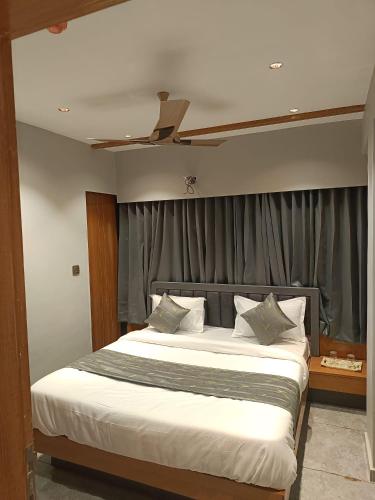 een slaapkamer met een groot bed en een plafondventilator bij Relax Inn - Drive In Road in Ahmedabad