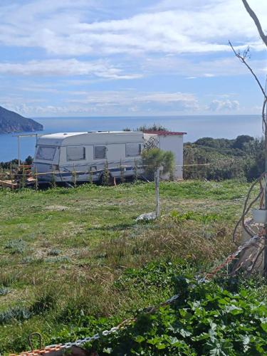 an rv parked in a field next to the ocean at Fox Caravan in Afionas