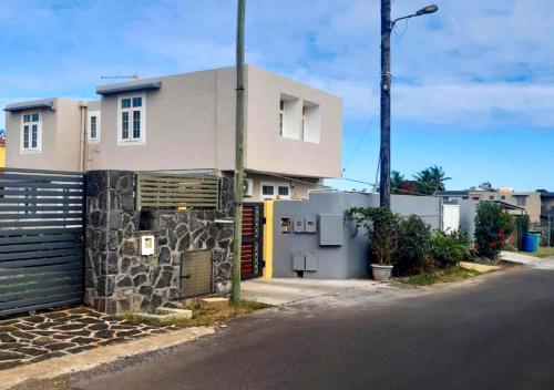 uma casa branca com um portão e uma rua em R Garden Studio 2 moderne pour couple dans un cadre relaxant et confortable em Port Louis
