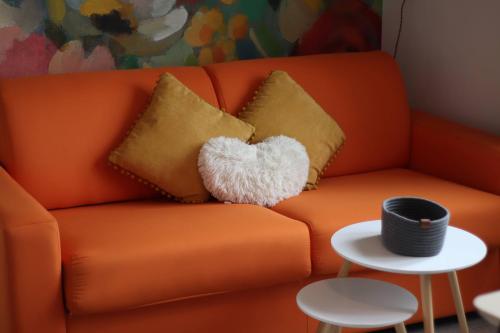 an orange couch with two pillows on a table at Top Appart - Parc Expo- Proche Musée de l Air- Proche parc Astérix in Le Blanc-Mesnil