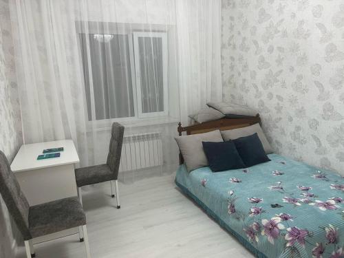 a bedroom with a bed and a table and a desk at 3-комнатные Апартаменты LUX in Taraz