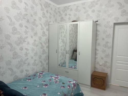 a bedroom with a white cabinet and a bed at 3-комнатные Апартаменты LUX in Taraz