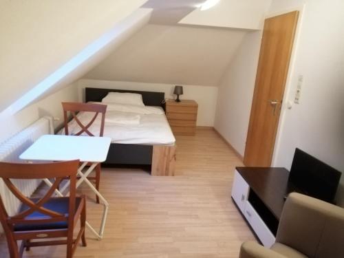 een kleine kamer met een bed en een tafel en stoelen bij Zimmervermietung Gasthof Lamm, Zugang selbstständig über Schlüsseltresor in Dettingen unter Teck