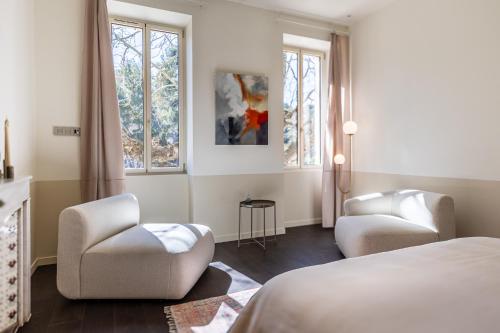 a bedroom with two chairs and a bed and windows at La Re-Source, propriété idéale pour séminaires et réunions in Alleins