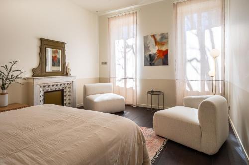 a bedroom with a bed and two chairs and a fireplace at La Re-Source, propriété idéale pour séminaires et réunions in Alleins