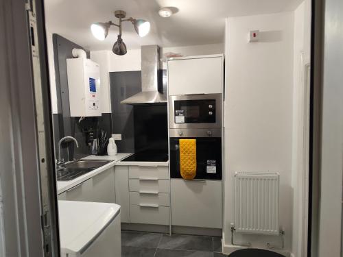 a kitchen with white cabinets and a microwave at home from home in Erith