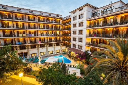 un immeuble d'appartements avec une piscine en face dans l'établissement Hotel La Carolina, à Lloret de Mar