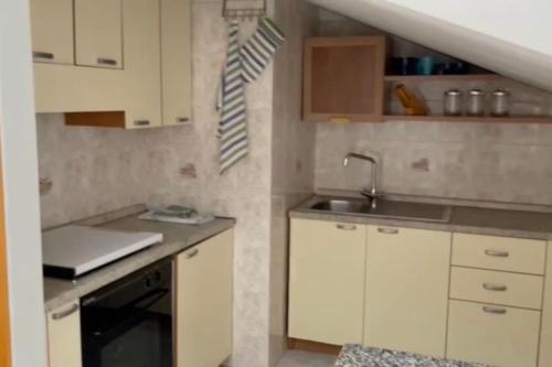 Elle comprend une petite cuisine avec des placards blancs et un évier. dans l'établissement Appartamento incantevole, Soverato, à Soverato Marina