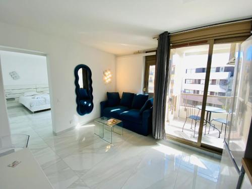a living room with a blue couch and a large window at Résidence Graziella appartement 410 in Juan-les-Pins