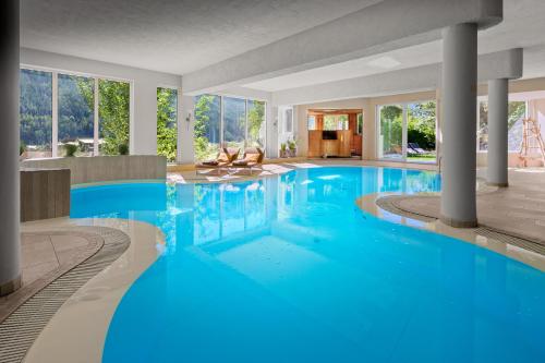 - une grande piscine d'eau bleue dans un bâtiment dans l'établissement Das Posthaus stubai&smart Hotel, à Fulpmes