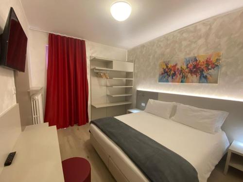 a bedroom with a white bed and a red curtain at Hotel Angelini in Nago-Torbole