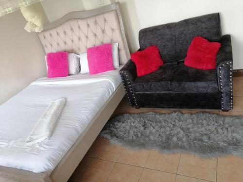 a couch with pink and black pillows and a chair at Joy suites emeli in Nairobi