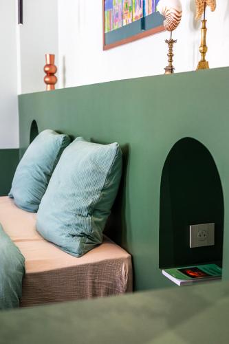 a bed with two pillows on it with a green wall at La Re-Source, propriété idéale pour séminaires et réunions in Alleins