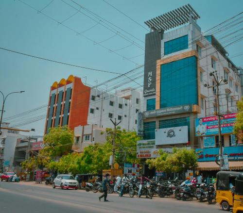 una concurrida calle de la ciudad con muchos edificios y motos en MSP Grands Inn, en Madurai