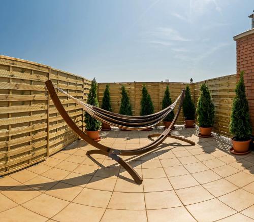 a hammock on a patio with a fence and trees at Arpad Bridge Apartments in Budapest