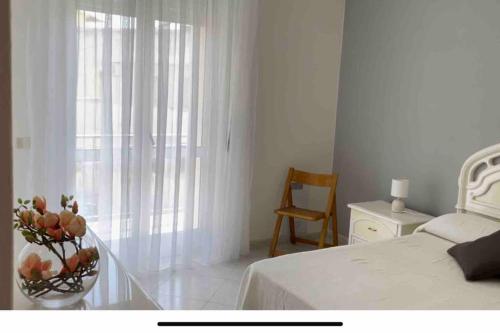 een slaapkamer met een bed en een vaas met bloemen op een tafel bij Appartamento centrale a Soverato in Soverato Marina