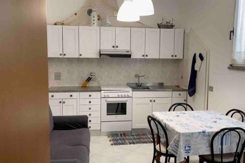 een keuken met witte kasten en een tafel met stoelen bij Appartamento centrale a Soverato in Soverato Marina