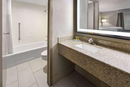 a bathroom with a sink and a toilet and a mirror at Days Inn by Wyndham Forsyth in Forsyth