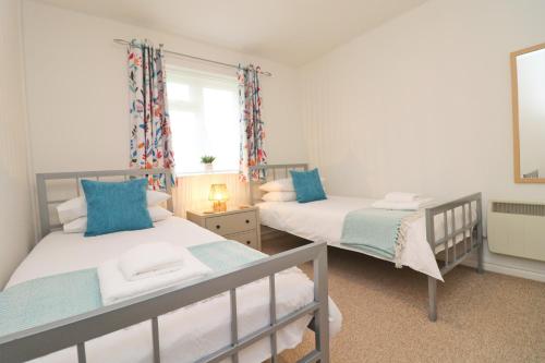 a bedroom with two beds and a window at 7 BAYS for 7 DAYS! Spacious bungalow near 7 beaches in Saint Merryn