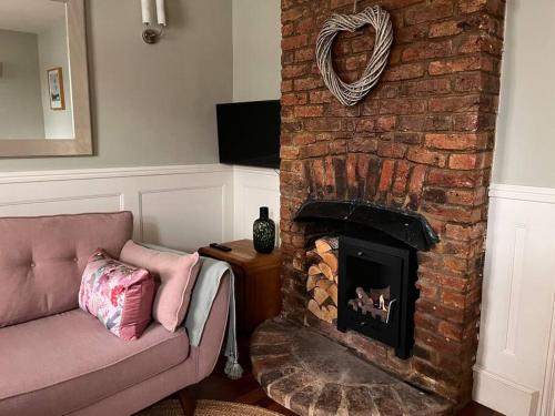 a living room with a couch and a brick fireplace at Contented Cottage - 2 Bedrooms, Zone 5 in Buckhurst Hill