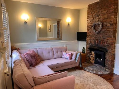 a living room with a couch and a fireplace at Contented Cottage - 2 Bedrooms, Zone 5 in Buckhurst Hill