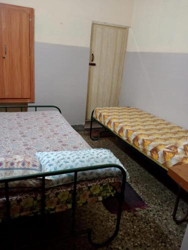 Zimmer mit 2 Betten und einem Holzschrank in der Unterkunft AMMAN LODGE in Tiruchchirāppalli