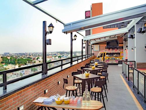 un restaurante con mesas y sillas en un balcón en ibis Bengaluru City Centre - An Accor Brand, en Bangalore