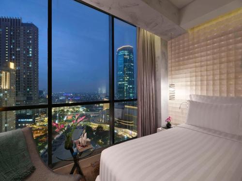 a bedroom with a bed and a large window at Pullman Jakarta Central Park in Jakarta