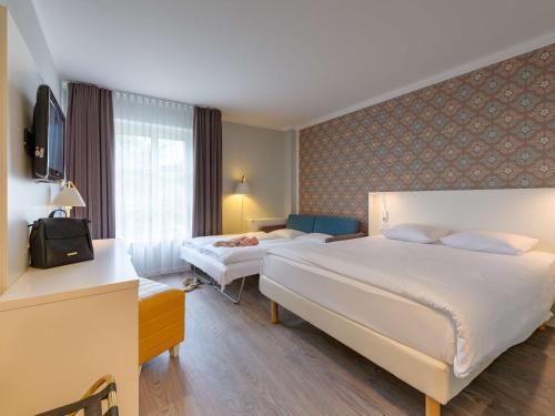 a hotel room with two beds and a television at Ibis Styles Regensburg in Regensburg