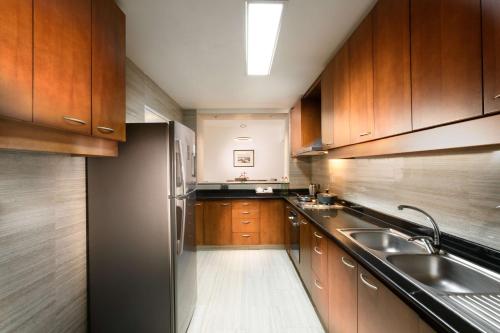 a kitchen with wooden cabinets and a stainless steel refrigerator at Hilton Colombo Residence in Colombo