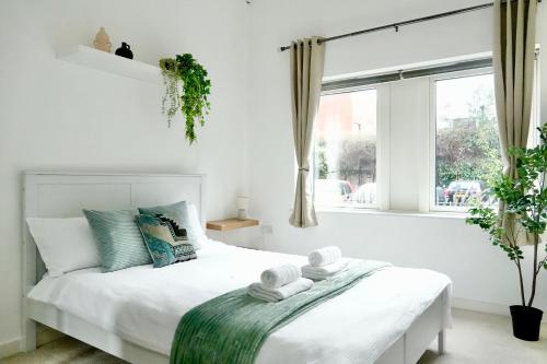 a white bedroom with a bed with towels on it at Luxury, Spacious 2 Bed flat in London in London