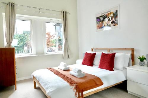 Schlafzimmer mit einem Bett mit roten und weißen Kissen in der Unterkunft Luxury, Spacious 2 Bed flat in London in London
