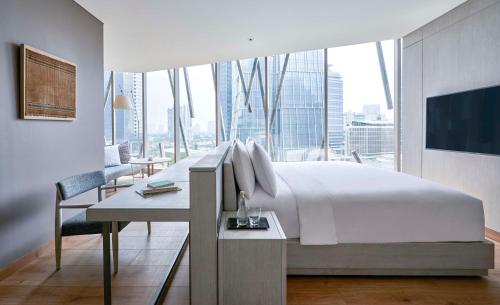 a bedroom with a bed and a desk and a large window at Alila SCBD Jakarta in Jakarta