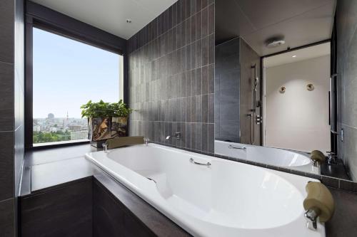 uma banheira na casa de banho com uma grande janela em Hyatt Centric Kanazawa em Kanazawa