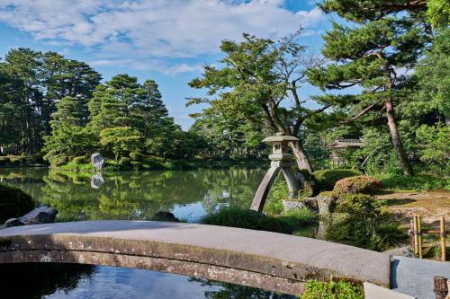 a bridge over a pond in a garden at Hyatt Centric Kanazawa in Kanazawa