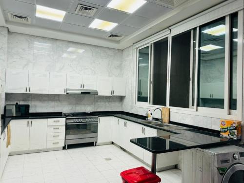uma cozinha com armários brancos e um balcão preto em Centerpoint Duplex Villa em Dubai