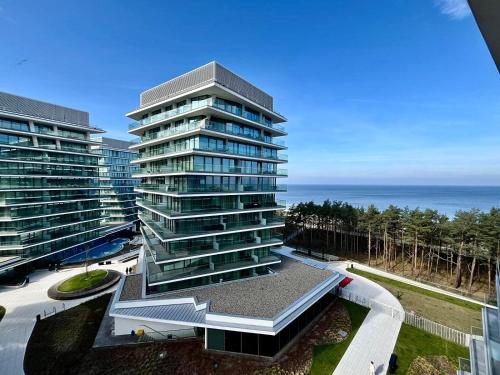 a tall building with the ocean in the background at Blue Reef 6th Floor Sea View Miedzyzdroje in Międzyzdroje